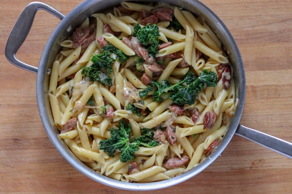 cooking pan with pasta sausage and kale