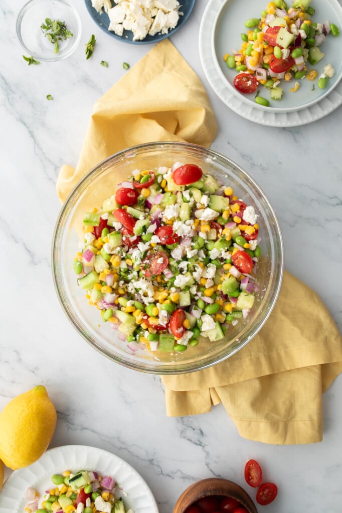 colorful corn edamame salad in glass bowl with yellow napkin under