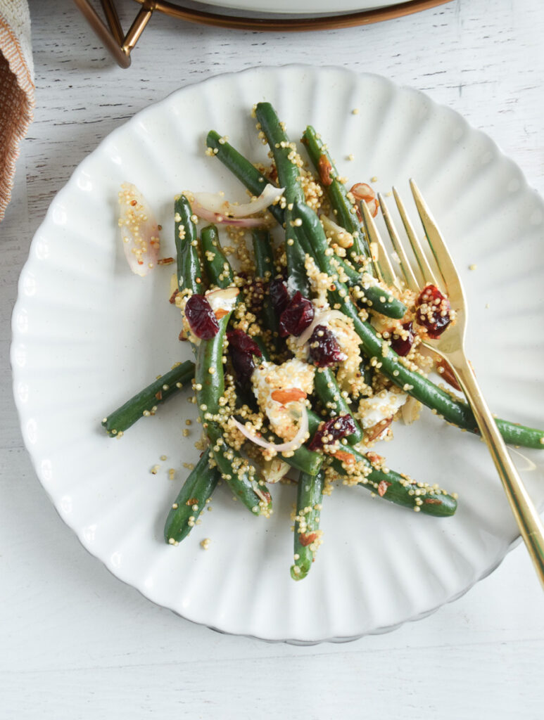 white plate with quinoa green beans and cranberries