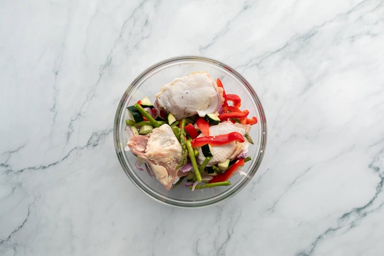 clear bowl with sliced veggies for sheet pan chicken 