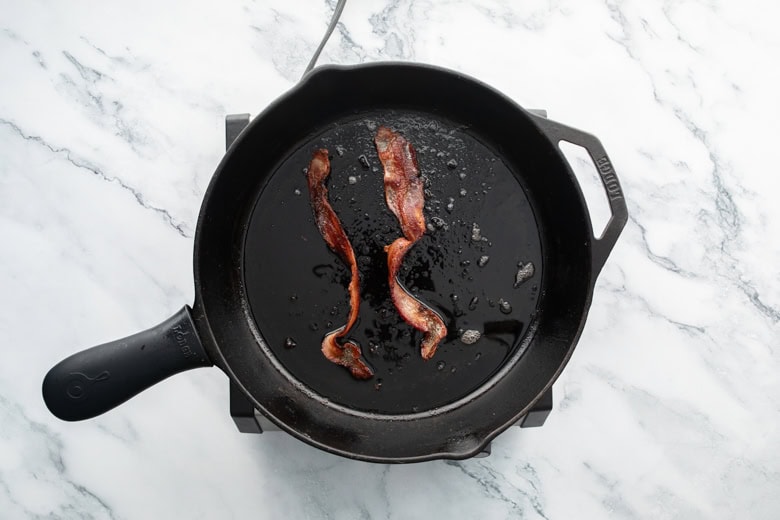 strips of crispy bacon in cooking skillet