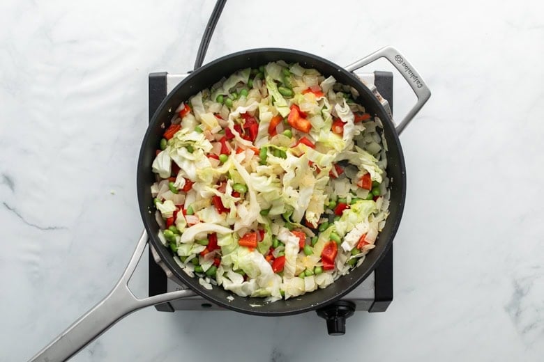 skillet with cabbage, edamame, onions and bell peppers to add to pork stir fry 