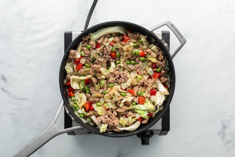 Delicious pork and vegetable stir fry with colorful peppers and cabbage in a skillet.