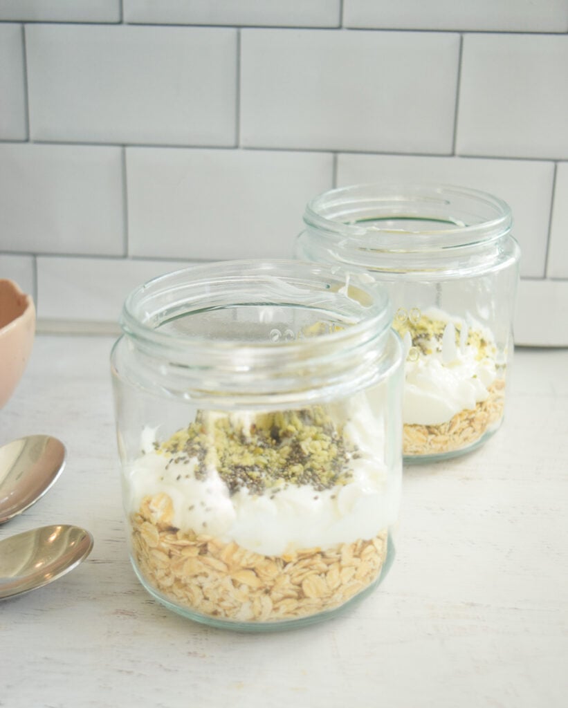Oats, yogurt and hemp seeds layered in mason jars for raspberry overnight oats