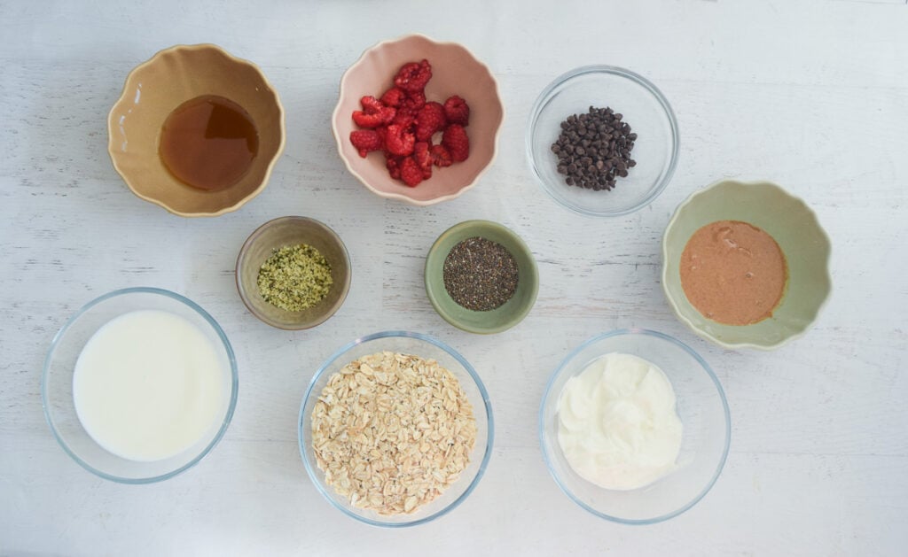 Glass jars of ingredients needed to combine to make raspberry overnight oats