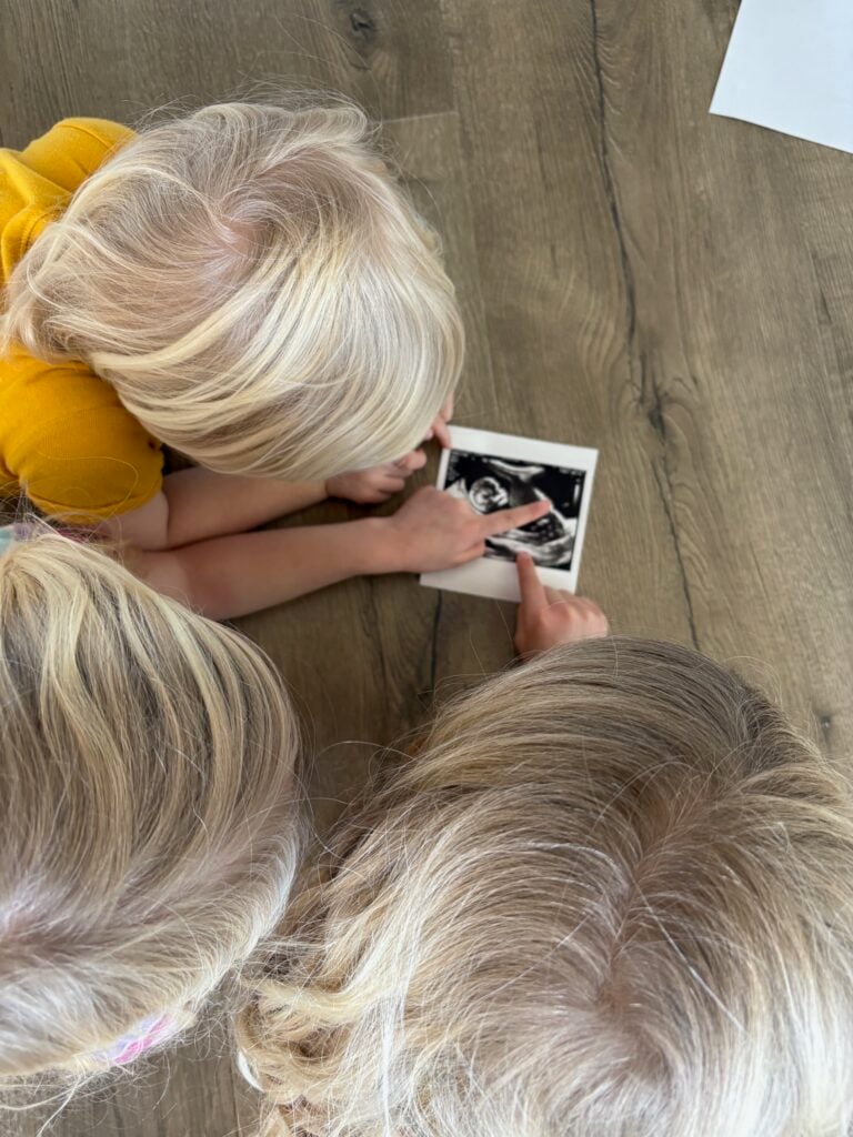 three kids looking at ultrasound picture of 4th child