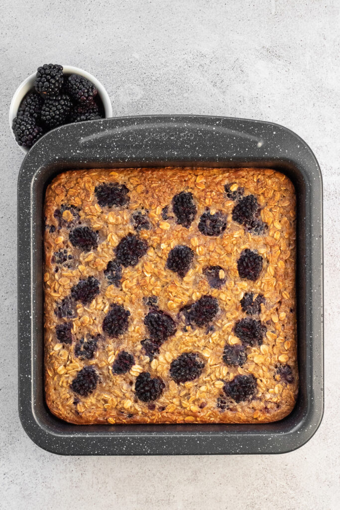 cooked blackberry baked oatmeal in 8x8 pan with fresh blackberries