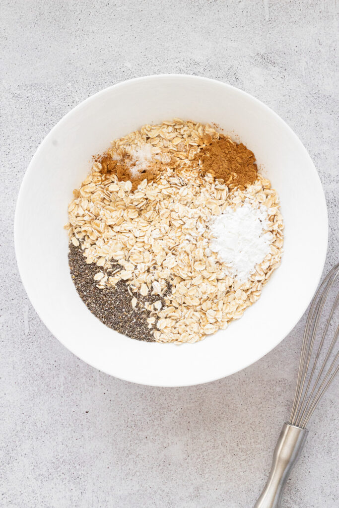 white bowl with oats and dry ingredients for blackberry baked oatmeal