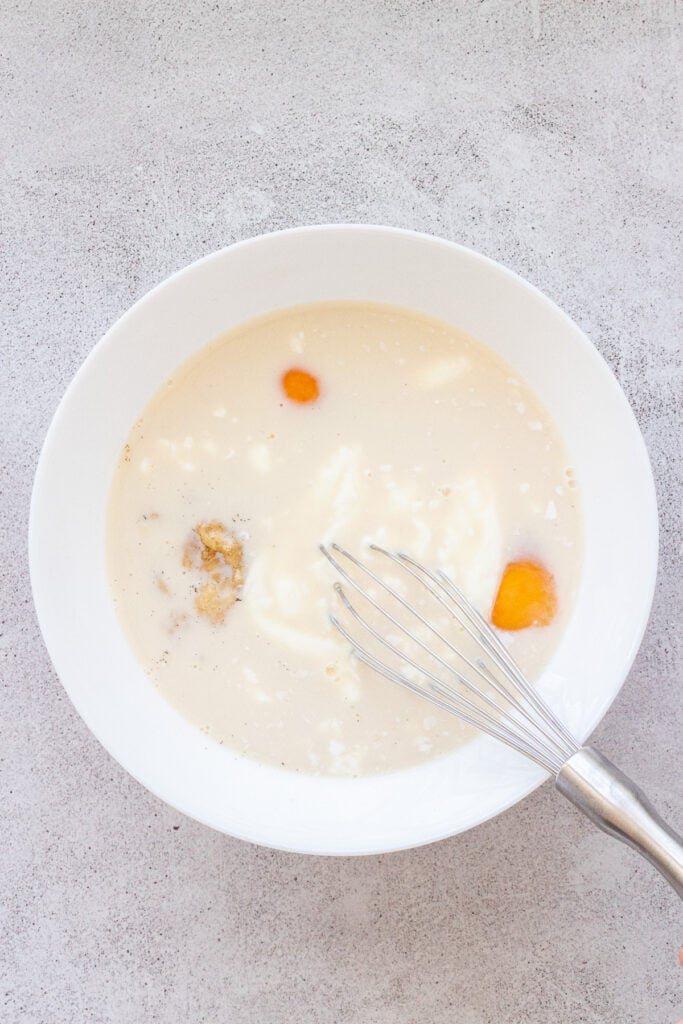 white bowl with mixed wet ingredients for blackberry oatmeal