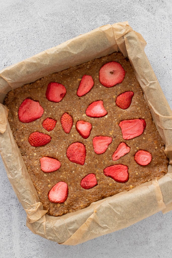 freeze dried strawberries on date oat bars batter in 8x8 baking pan. 