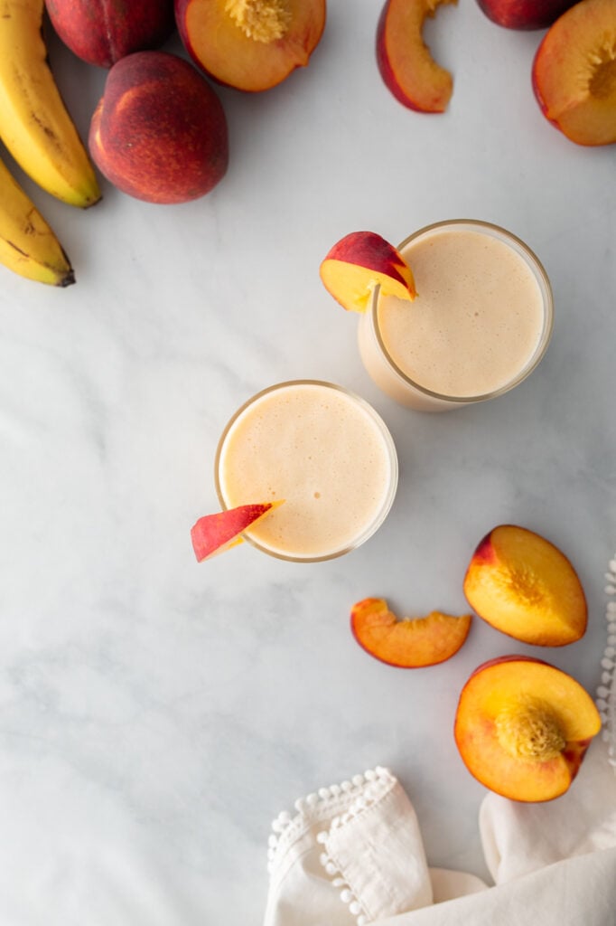 A creamy peach banana smoothie blended until perfectly smooth and topped with fresh peach slices.