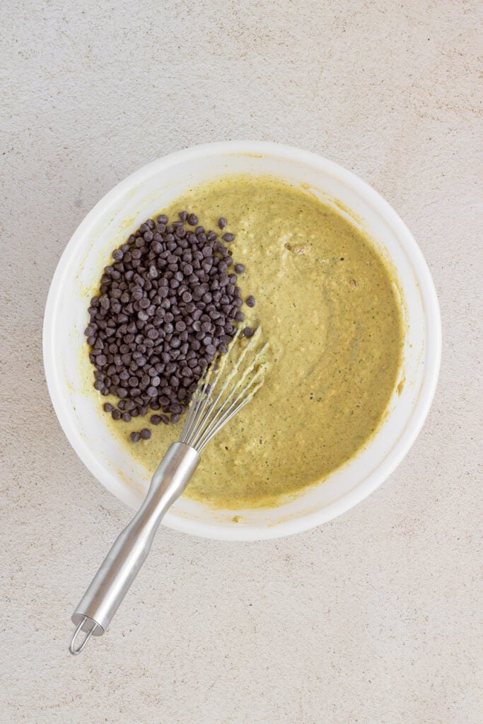 White bowl with spinach banana muffin batter and chocolate chips