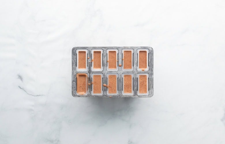 adding chocolate pudding mixture to popsicle molds