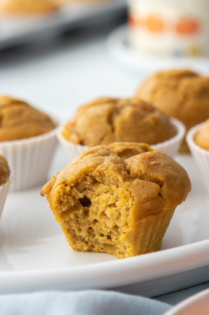 Healthy and fluffy pumpkin carrot muffins on a white plate with a blurred background.
