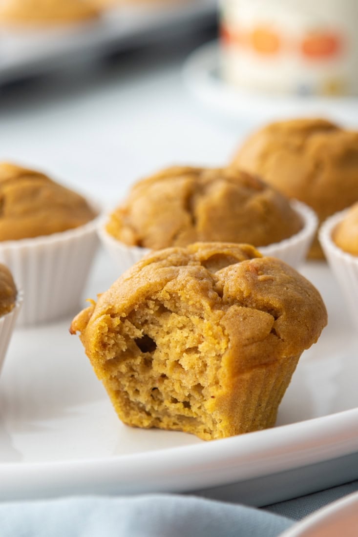 Healthy and fluffy pumpkin carrot muffins on a white plate with a blurred background.