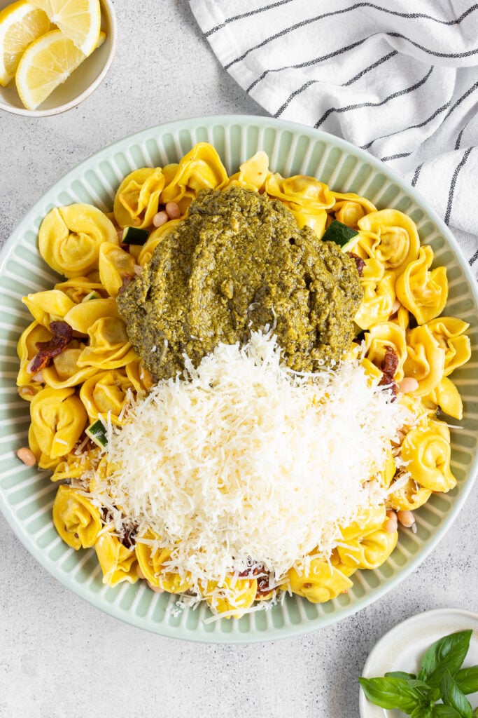 Cooked tortellini pasta salad with pesto and parmesan cheese to be spread