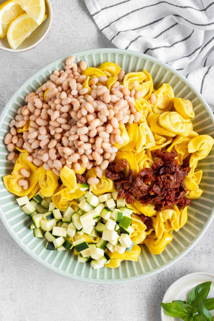 Tortellini pasta salad with white beans and sundried tomatoes on green plate