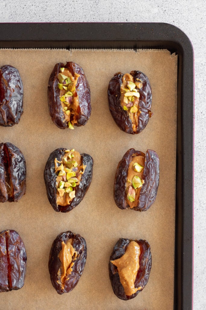 parchment paper with dates stuffed with peanut butter and pistachios