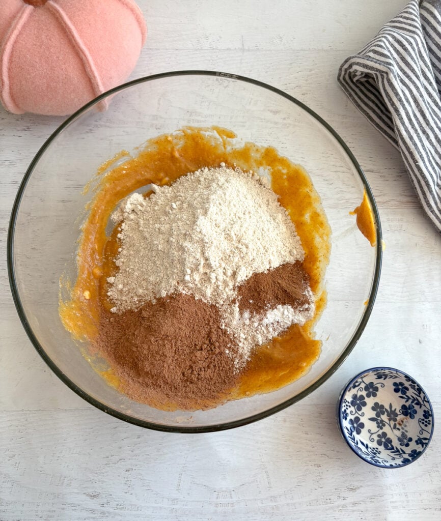glass mixing bowl with ingredients for chocolate pumpkin brownies.