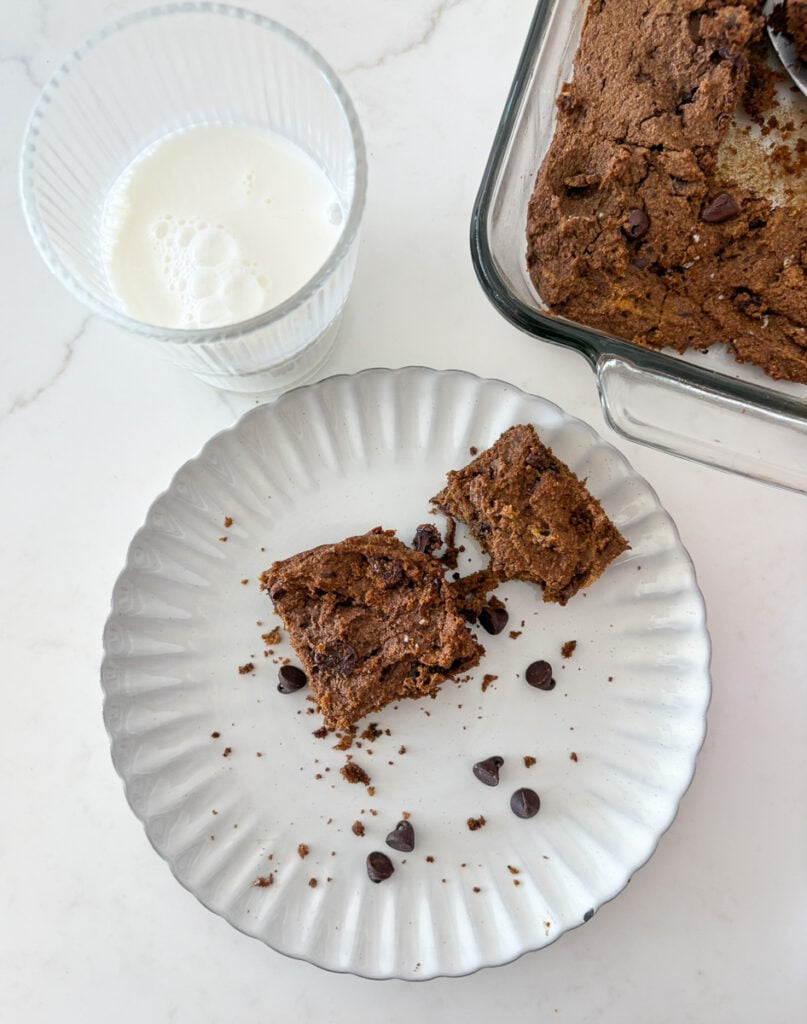 chocolate and pumpkin brownies on serving plate next to a glass of milk.